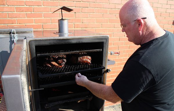 Roby Williams tends to pork butts that have smoked for eight hours at Smohk in Scott's Addition. (J. Elias O'Neal)